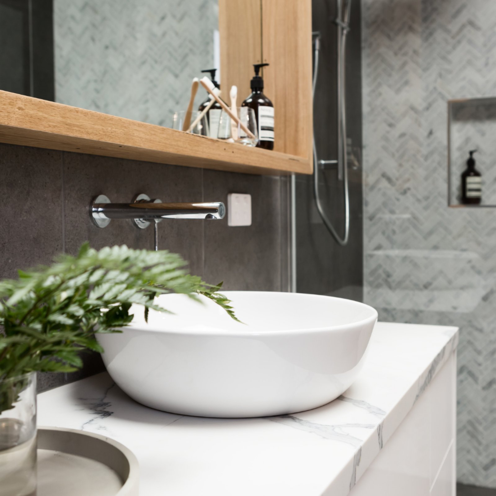 μοντέρνο μπάνιο με λευκό νιπτήρα και γκρι πλακάκι τοίχου. Έπιπλο μπάνιου λευκό με πάγκο που θυμίζει μάρμαρο